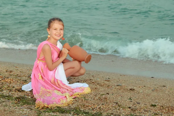 Ler söt liten flicka i en vacker klänning i grekisk stil — Stockfoto