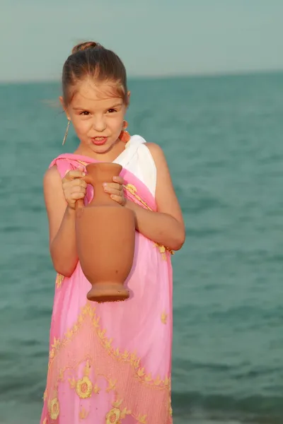 Ler söt liten flicka i en vacker klänning i grekisk stil — Stockfoto