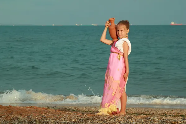 Lächelnd niedliches kleines Mädchen in einem schönen Kleid im griechischen Stil mit einer Amphore — Stockfoto