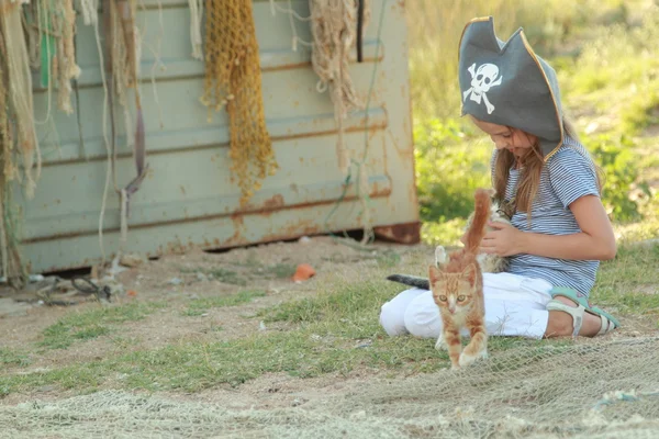 Linda niña en un sombrero pirata sosteniendo gatito en la naturaleza —  Fotos de Stock