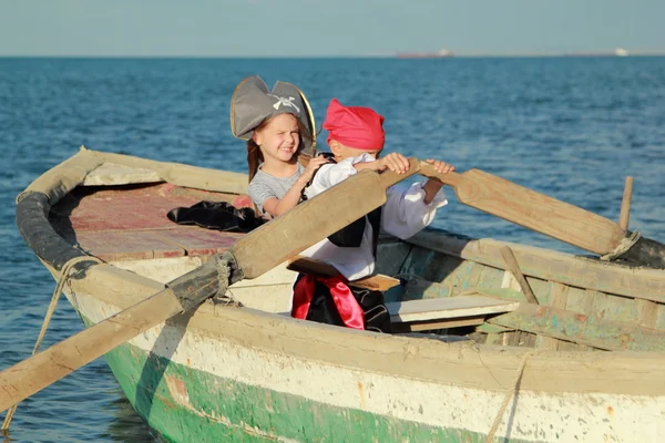Joyful young children playing pirates in the old dirty boat in the sea — Stockfoto
