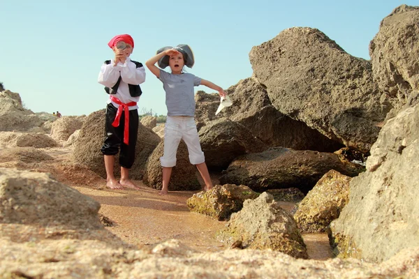 Joyful little girl and boy in fancy dress pirate sitting on the shore of the sea — Stock Photo, Image
