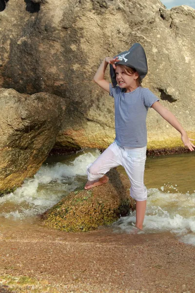 Alegre dulce joven chica en un pirata sombrero está descalzo en el agua del mar en un día de verano — Foto de Stock