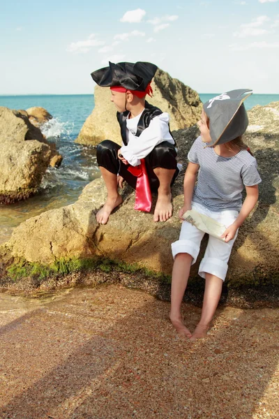 Menino e menina em um traje de pirata com um mapa e uma lupa — Fotografia de Stock