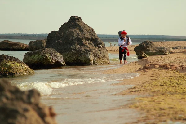 Cheerful smiling young boy and girl in pirate costumes barefoot running by the sea in hot summer day — Stock Photo, Image