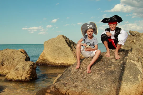 Beaux jeunes enfants pirate garçon et fille tenant une carte de pirate et une loupe — Photo