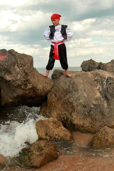 Portrait of a cute young boy dressed as a pirate standing on the seashore — Stock Photo, Image