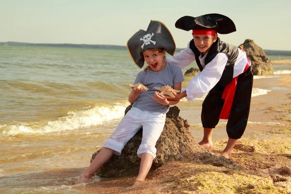 Lindo niño con un disfraz de pirata y una niña pequeña con un sombrero con un símbolo de esqueleto —  Fotos de Stock