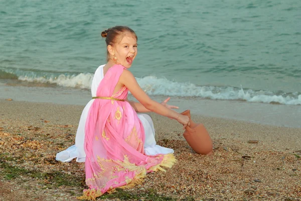 Lächelnd niedliches kleines Mädchen in einem schönen Kleid im griechischen Stil mit einer Amphore — Stockfoto