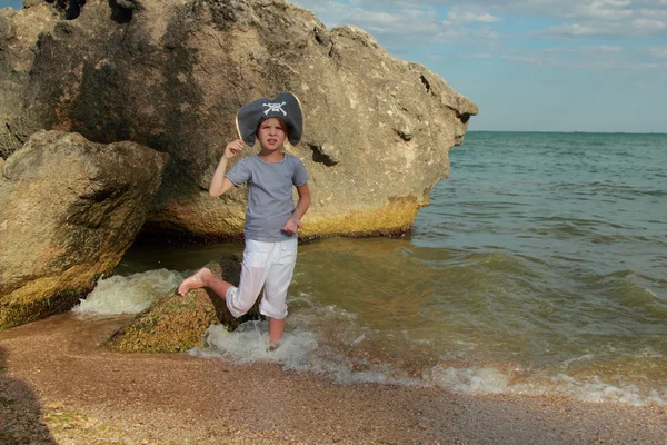 Charmig ung flicka i en pirat hatt stående i vatten på stranden i sommar — Stockfoto