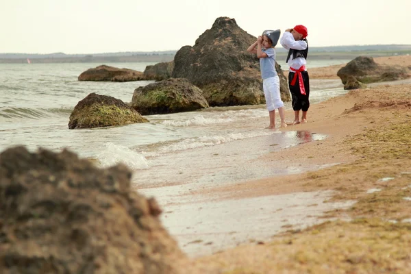 Веселые счастливый милый мальчик и девочка в пиратских костюмах босиком бегать по побережью моря — стоковое фото