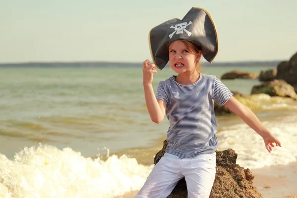 Beautiful angry little girl in pirate fancy dress on a background of a sea landscape — Stock Photo, Image