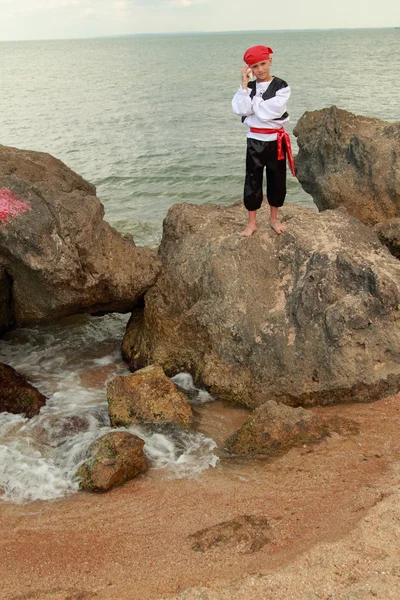 Portrait of a cute young boy dressed as a pirate standing on the seashore — Stock Photo, Image