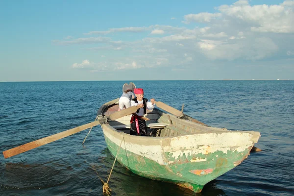 Joyful young children playing pirates in the old dirty boat in the sea — Stock Photo, Image