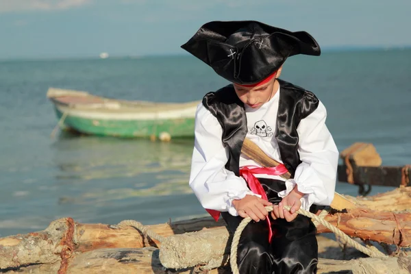 Affascinante giovane pirata ragazzo in una bandana rossa in piedi sullo sfondo del mare blu — Foto Stock