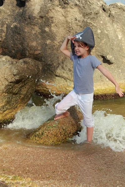 Korsanlık bir iskelet korsan ile şapkalı güzel küçük kız su büyük bir kaya deniz kenarında mevcuttur — Stok fotoğraf