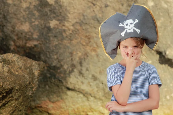 Allegro dolce ragazza in un cappello da pirata si trova a piedi nudi nell'acqua del mare in una giornata estiva — Foto Stock