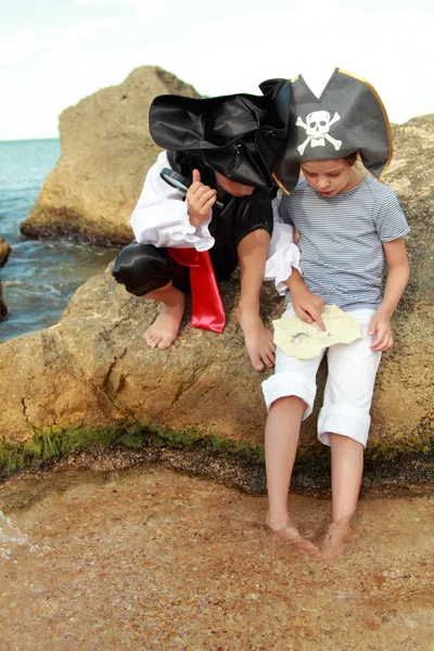 Bonitas crianças piratas menino e menina segurando um mapa pirata — Fotografia de Stock