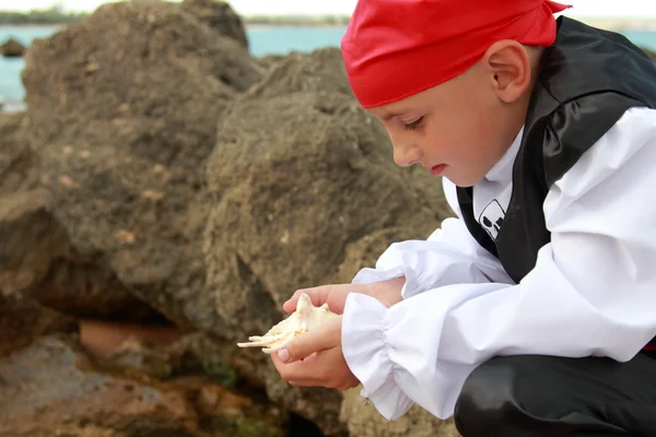 Retrato de um menino bonito vestido como um pirata em pé na praia — Fotografia de Stock