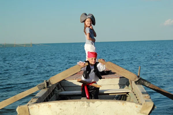 Neşeli bir çocuk ve korsan oynayan kız gülümseyerek takım elbise ve şapka giymiş — Stok fotoğraf