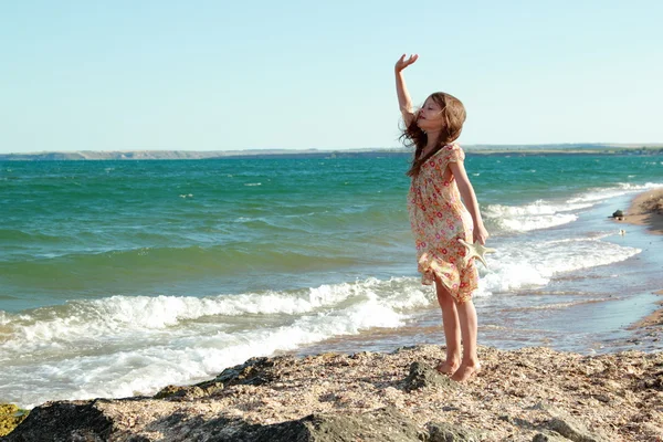 Chica encantadora con una hermosa sonrisa jugando descalzo en el agua en la playa —  Fotos de Stock