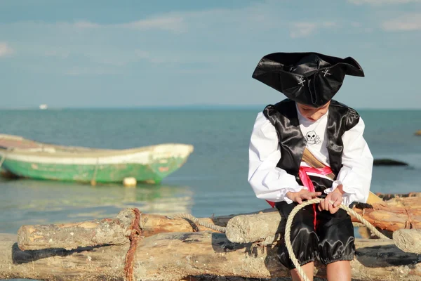 Handsome Boy dressed as a pirate on the sea coast — Stockfoto