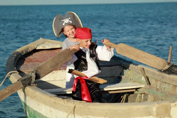 Радостные маленькие дети играют в пиратов на старой грязной лодке в море — стоковое фото