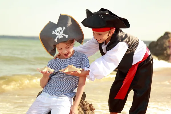 Menino bonito em um traje de pirata e uma menina em um chapéu com um esqueleto — Fotografia de Stock