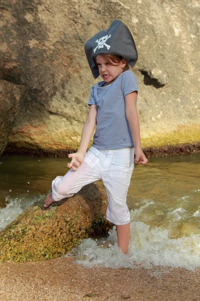 Affascinante ragazza con un cappello da pirata in piedi in acqua sulla spiaggia in estate — Foto Stock