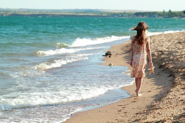 Piękny wesoły uśmiechający się mała dziewczynka tańczy na plaży w słoneczny letni dzień — Zdjęcie stockowe