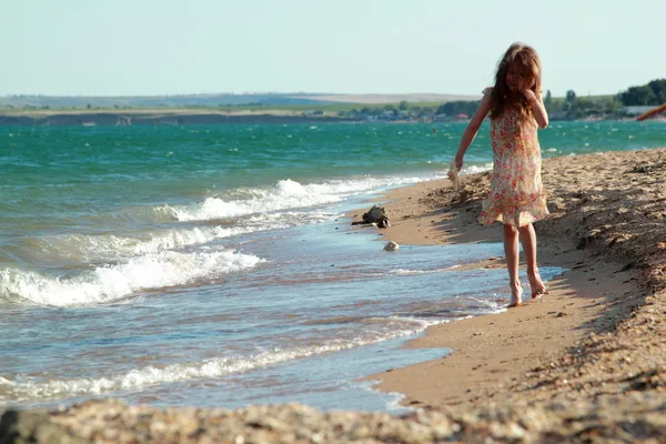 Vakker, glad, liten jente som danser på stranden om sommeren, solfylt dag – stockfoto