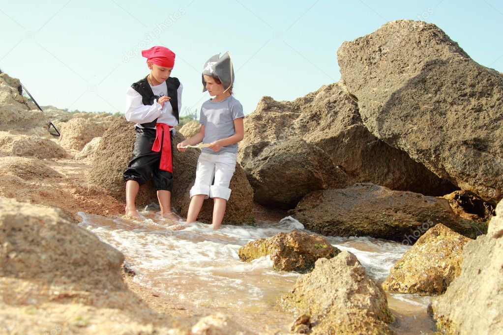 European children smiling boy and girl in fancy dress pirate looking for buried treasure