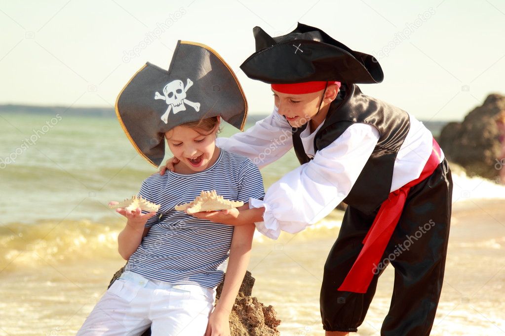 Cute little boy in a pirate costume and a little girl in a hat with a skeleton