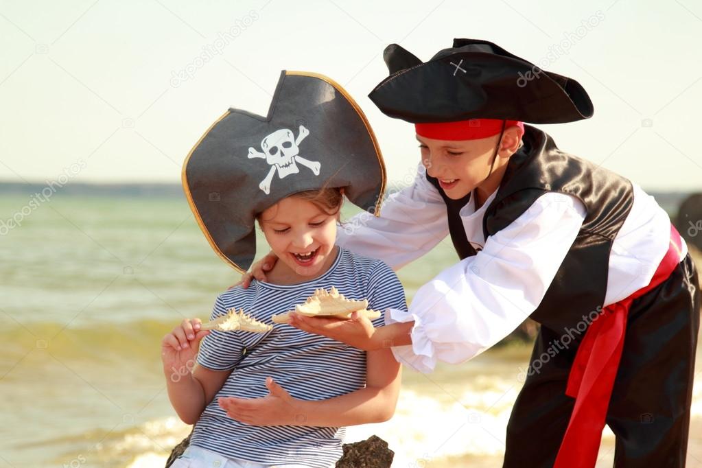 Cute little boy in a pirate costume and a little girl in a hat with a skeleton symbol of piracy