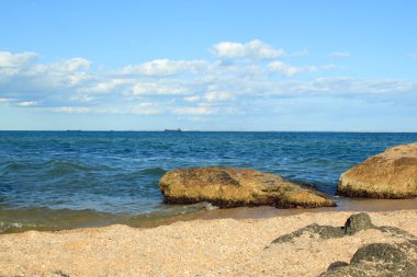 Deniz ve gün güneşli yaz sahilde büyük taşlarla deniz manzara.
