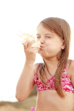 güzel bir deniz kabuğu tutan bir mayo bir gülümseyen sevimli küçük kız portresi.