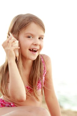 güzel bir deniz kabuğu tutan bir mayo bir gülümseyen sevimli küçük kız portresi.