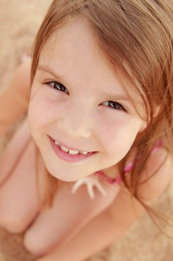 Avrupa gülümseyen kız deniz kum bir arka plan üzerinde oturan bir pembe mayo