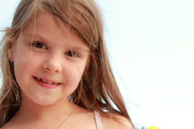 Caucasian lovely little girl smiling on a background of blue sea