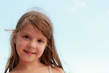Caucasian lovely little girl smiling on a background of blue sea