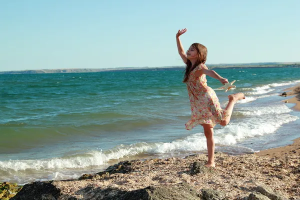 Entzückend glückliches kleines Mädchen hält einen Seestern am Strand in den sonnigen Tag — Stockfoto
