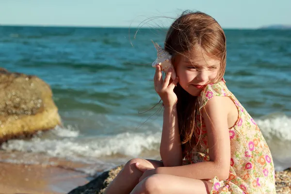 Retrato de uma jovem menina feliz em um vestido de verão com uma concha — Fotografia de Stock