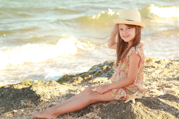 Portrait of a little girl who dreams of a hat on a background of a sea landscape — Stock Photo, Image