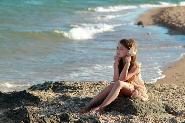 Portrait of a happy young girl in a summer dress with a seashell — Stock Photo, Image