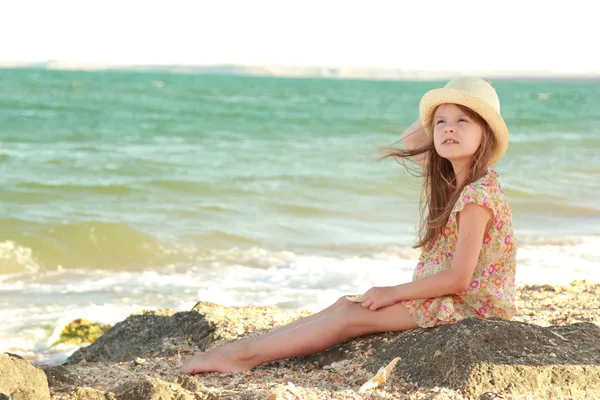 Портрет маленькой девочки, мечтающей о шляпе на фоне морского пейзажа на открытом воздухе — стоковое фото