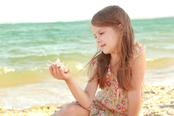 Retrato de uma jovem menina feliz em um vestido de verão com uma concha . — Fotografia de Stock