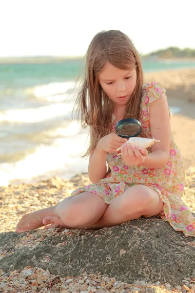 Portret van een schattig klein meisje met dromen van een glimlach en houden een zeeschelp. — Stockfoto