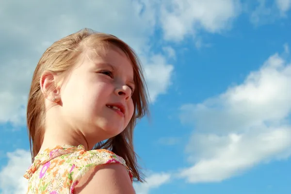 Retrato de menina sorridente bonito em um fundo de céu azul com nuvens ao ar livre . — Fotografia de Stock