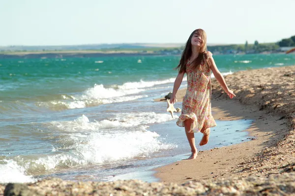 Piękne dziewczyny z pięknym uśmiechem gra boso w wodzie na plaży. — Zdjęcie stockowe