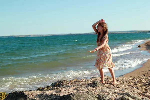 Szép vidám mosolygós kislány táncol a parton a nyári napsütésben. — Stock Fotó